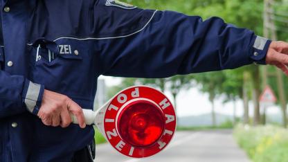 Symbolbild HIV bei der Polizei: polizist winkt auto mit Stopschild aus dem verkehr
