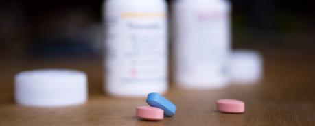 Postexpositionsprophylaxe (PEP) als Notfallmaßnahme nach Safer-Sex-Unfall Vor zwei geöffneten Tablettendosen liegen zwei rosane und eine blaue Tablette.
